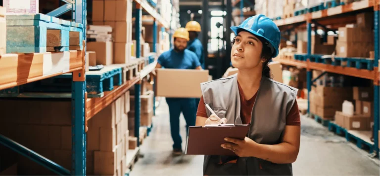Woman in Blue Hardhat writing on a Clipboard