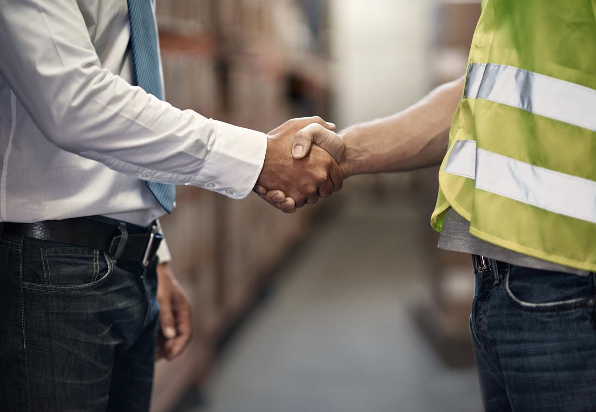 Two colleagues shaking hands in a warehouse