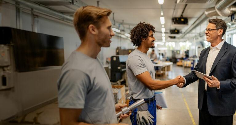 Two men shaking hands in a manufacturing setting